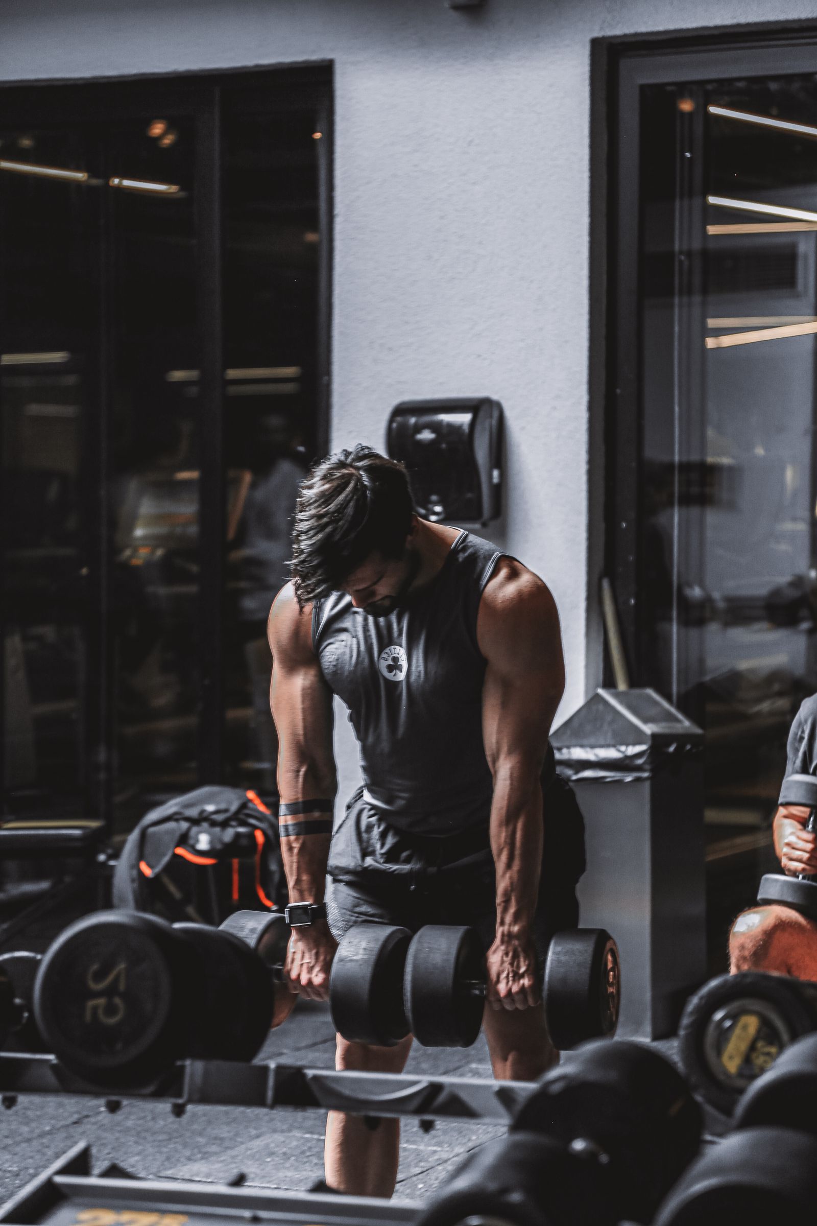 Hombre musculoso levantando mancuernas pesadas en el gimnasio para hipertrofia