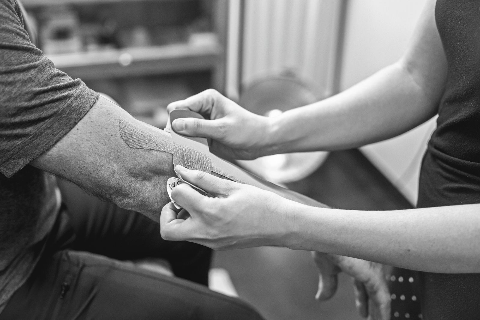 Fisioterapeuta aplicando kinesiotape en el codo para tratar epicondilitis